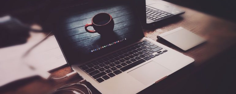 A laptop with a cup on the screen